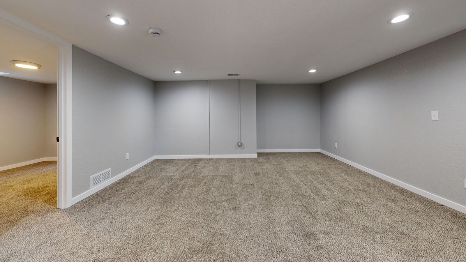 Finished basement family room with warm lighting and new flooring